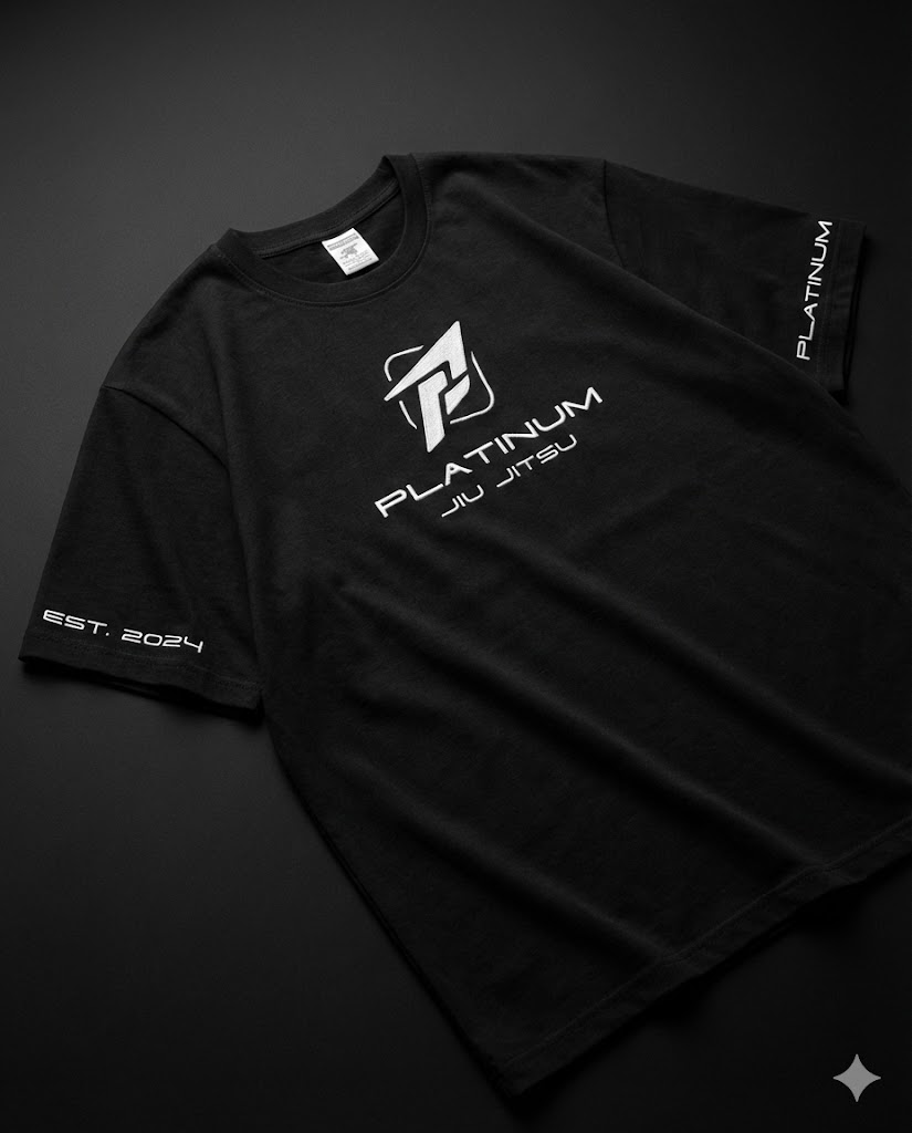 Black Platinum Jiu Jitsu t-shirt flat lay on dark background, white logo on chest, EST 2024 text on sleeve, premium BJJ lifestyle apparel.